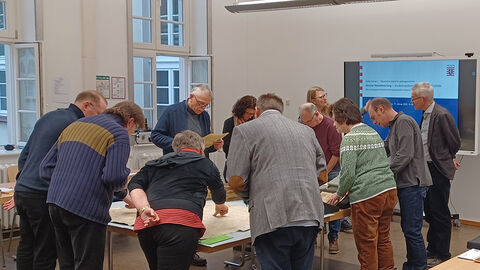 Teilnehmerinnen und Teilnehmer des Seminars betrachten für die Lokalforschung wichtige Originalquellen aus dem Staatsarchiv Marburg